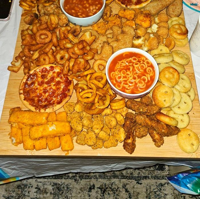 Kids party food board with pizza, chicken nuggets, fish fingers, beans and dips