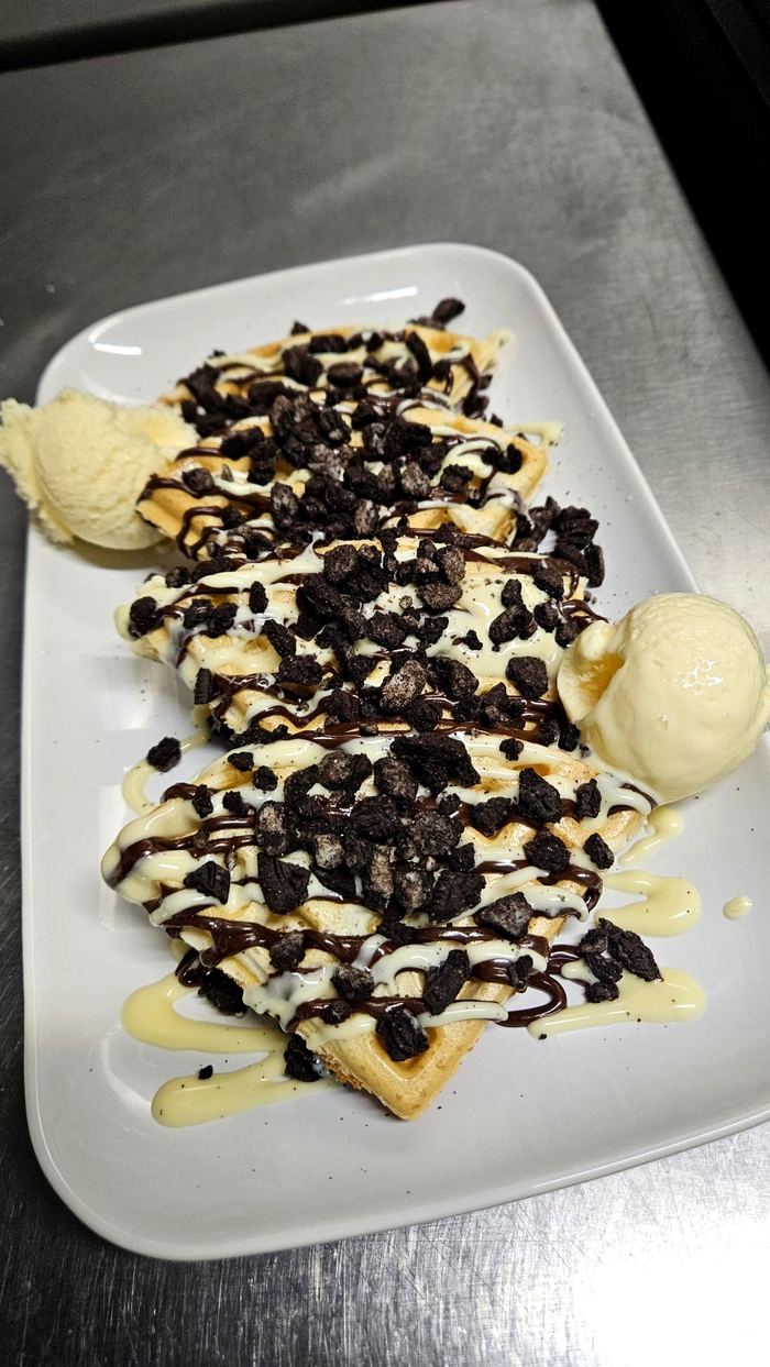 Waffles topped with crushed Oreo biscuit and chocolate drizzle